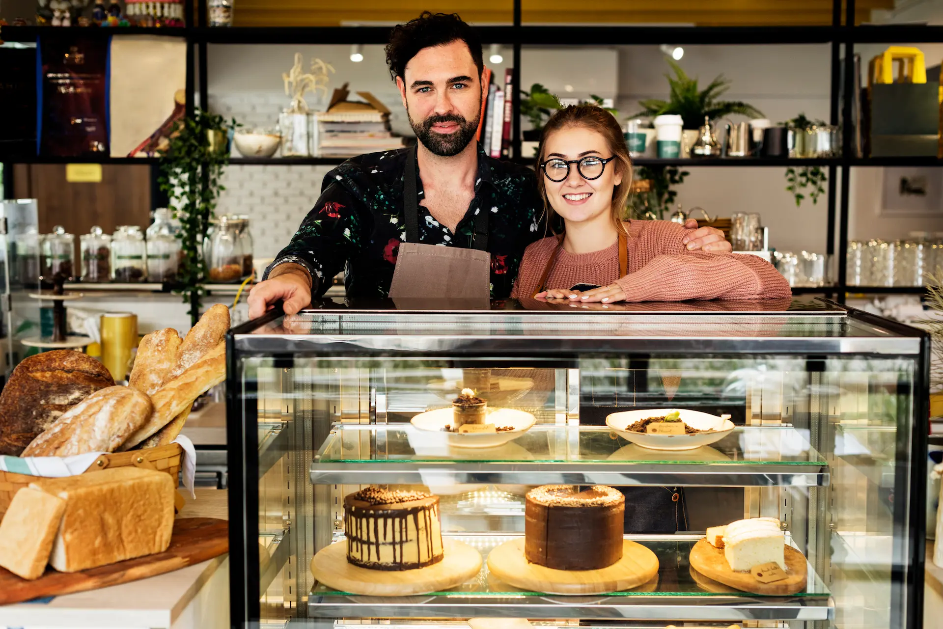 Bakery business owners standing behind a showcase of their decadent desserts and rustics breads