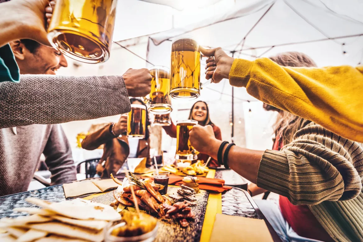 A group of people raising a cheers at a table full of charcuterie at a special brewery event